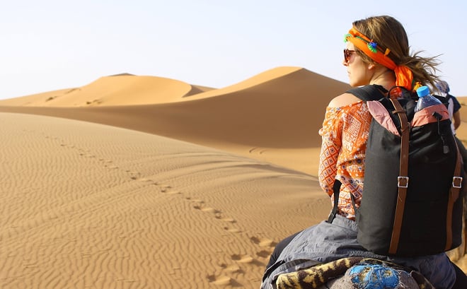 Traveler riding a camel through Dubai desert dunes